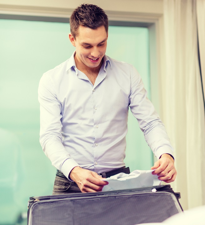 man_packing_luggage_smiling